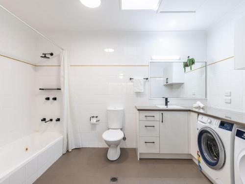 a white bathroom with a toilet and a washing machine at Villa 121 Horizons in Salamander Bay