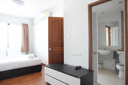 a bedroom with a bed and a bathroom with a mirror at V-twin Donjan Service Apartment in Chiang Mai