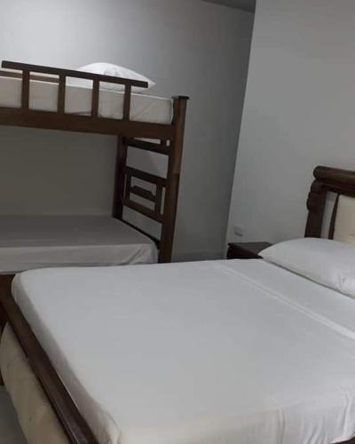 a room with two bunk beds and a white bed at Hostal Y Balneario La Danta in El Zaino