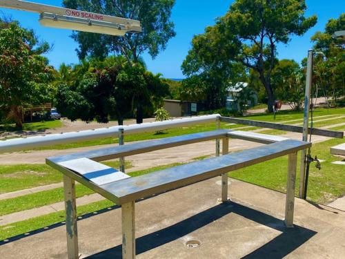 
a wooden bench sitting on top of a sidewalk at Orchid Beach Apartments in Fraser Island
