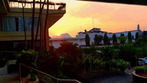 a sunset view of a building and a garden at Grand Sunshine Resort & Convention in Bandung
