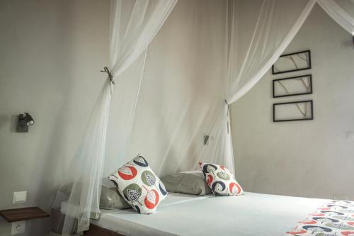 a bedroom with a bed with a canopy and pillows at Chez Senga in Madirokely