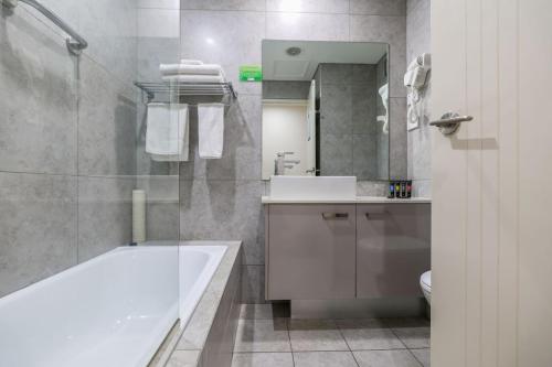 a bathroom with a sink, toilet and bathtub at Argus Hotel Darwin in Darwin