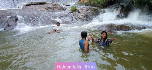 two people in the water near a waterfall at Doddakallu Betta Homestay Coorg in Somvārpet