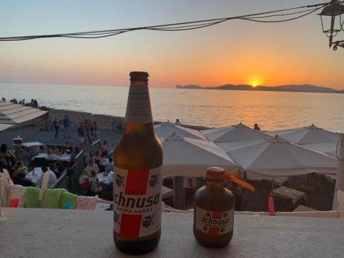 two bottles of beer sitting on a table at the beach at Alghero Old Town Gem - Emerald in Alghero