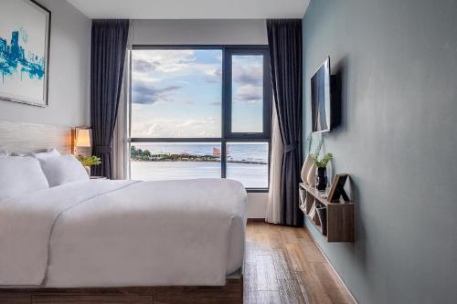 a hotel room with a large bed and a large window at Oakwood Hotel & Residence Sri Racha in Si Racha
