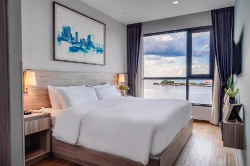 a bedroom with a large white bed and a large window at Oakwood Hotel & Residence Sri Racha in Si Racha