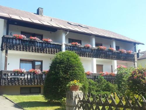 ein Haus mit einem Balkon mit Blumen darauf in der Unterkunft Ferienwohnungen Hopfen und Malz in Fichtelberg