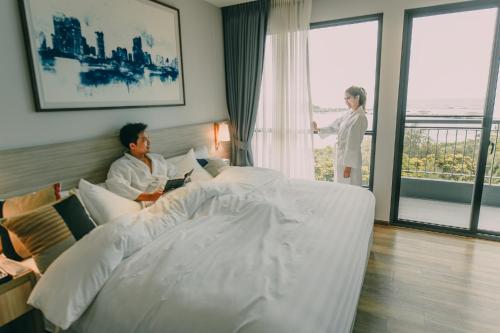 a woman standing next to a bed in a hotel room at Oakwood Hotel & Residence Sri Racha in Si Racha