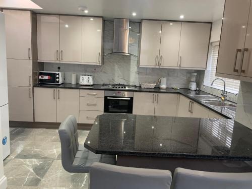 a kitchen with white cabinets and a black counter top at Beautiful All room En-suite 4 bedrooms house , Free parking, WiFi, Corporate, Contractors, Family relocation, CONTACT US FOR LONG TERM RATE in Ilford