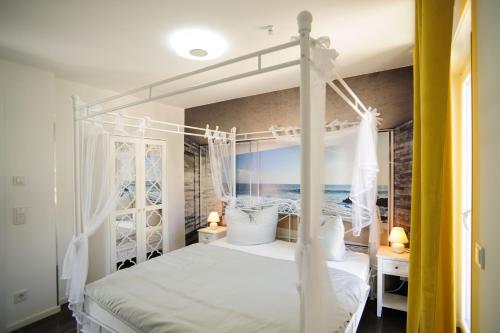 Un dormitorio con una cama blanca con dosel y el océano en Designpension Idyll Nr 3 - Hotel Garni - Sennhütte 1, en Wernigerode