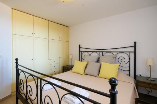 a bedroom with a black bed with yellow pillows at Stella Di Mare family house in Agios Ioannis Tinos