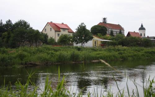 un grupo de casas junto a un cuerpo de agua en Dom pod Czarnym Bocianem, en Tykocin