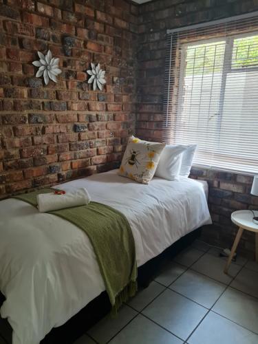 Cama en habitación con pared de ladrillo en The Honeycomb en Kimberley