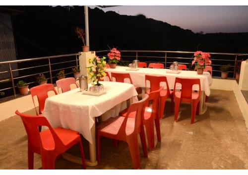 een groep tafels en stoelen met bloemen op een balkon bij Forest Villa Banglow 6BHK in Panchgani