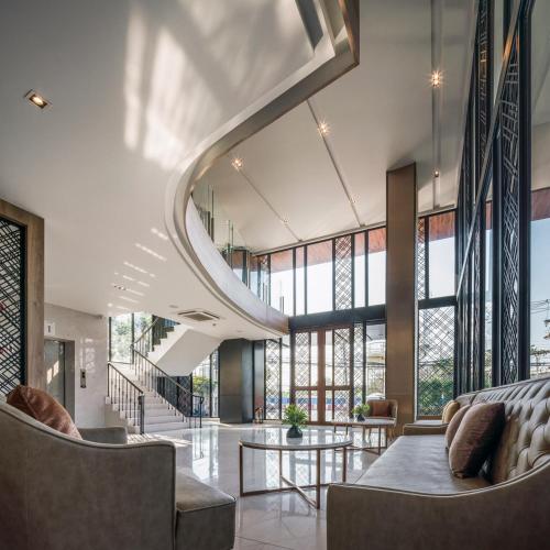 an open lobby with a spiral staircase and chairs at Zayn Hotel Bangkok - Airport Link Access in Bangkok