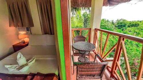 a room with a balcony with a bed and a table at Ananda Resort in Panglao