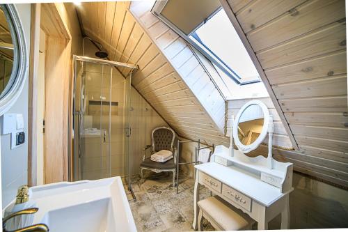 La salle de bains mansardée est pourvue d'un lavabo et d'un miroir. dans l'établissement Karpacz-Sosnówka apartamenty butikowe z widokiem na góry, à Sosnówka