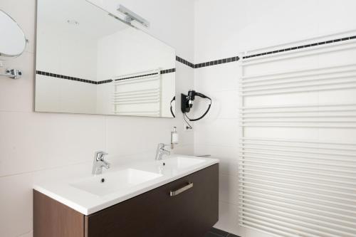 een badkamer met een wastafel en een douche met een spiegel bij Smartflats Design - Opera in Luik