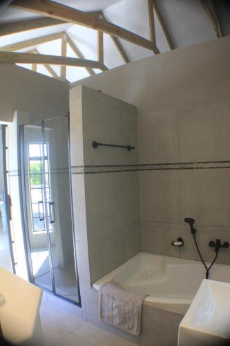 La salle de bains est pourvue d'une baignoire et d'une douche. dans l'établissement Pecan Tree Cottage, à Montagu