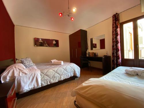 1 dormitorio con 2 camas, escritorio y ventana en Dolce Estate Cefalù, en Cefalú