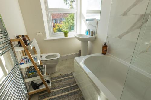 a bathroom with a tub and a toilet and a window at Amazing new 3 double bed house in staple hill! in Bristol