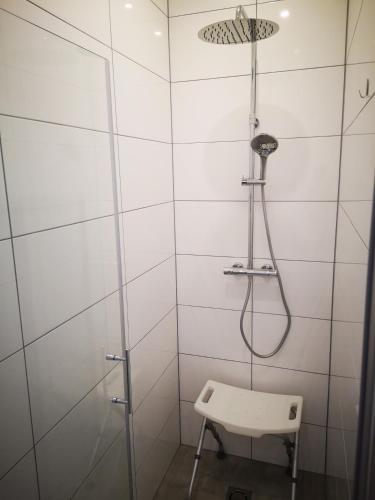 a shower in a white tiled bathroom with a stool at APARTMENT WALD - im Skigebiet Gerlitzen & Ossiacher See in Bodensdorf