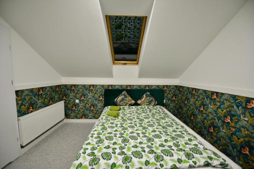 a small bedroom with a bed with a floral bedspread at Pokoje Gościnne u Klimosza in Pogwizdów