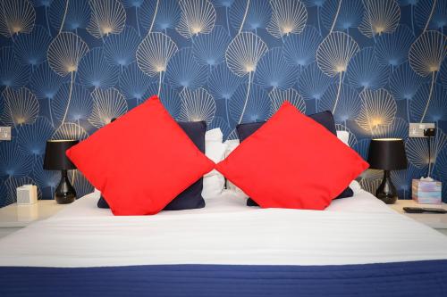 uma cama com duas almofadas vermelhas e uma parede azul em The Ashleigh - Dog Friendly em Bournemouth