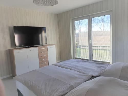 a bedroom with a bed and a flat screen tv at Ostsee-Luxus-Ferienwohnung Sanitz in Sanitz