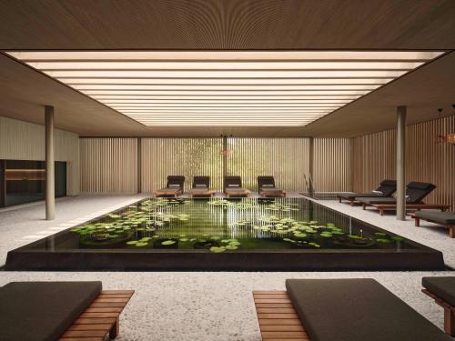 a lobby with a pond with chairs and a table at Patina Maldives, Fari Islands in North Male Atoll