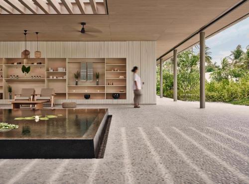 a person is standing in a living room with a large window at Patina Maldives, Fari Islands in North Male Atoll