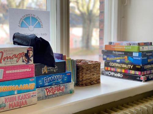a stack of books sitting on a shelf next to a window at Hostel Suomenlinna in Helsinki