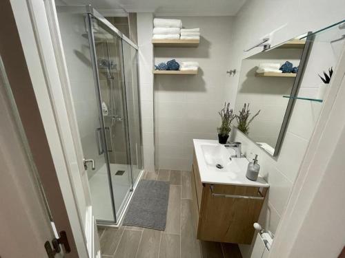 y baño con ducha acristalada y lavamanos. en Apartamento Entrebateas en Aldán