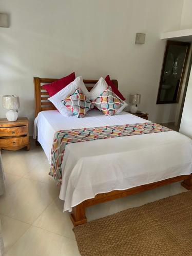a bedroom with a bed with white sheets and red pillows at SOUTH HILL VILLA in Mahe