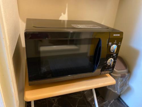a microwave sitting on top of a wooden stand at Melody Heim 2C in Tokushima