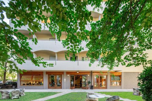 ein großes Gebäude mit Glastüren und Bäumen in der Unterkunft Hotel La Pergola Dependance in Lignano Sabbiadoro