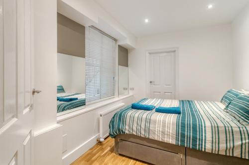una camera bianca con un letto e una finestra di Holland Park Apartment a Londra