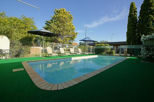 a swimming pool with chairs and an umbrella at Nicholas Royal Motel - No Pets Allowed in Hay