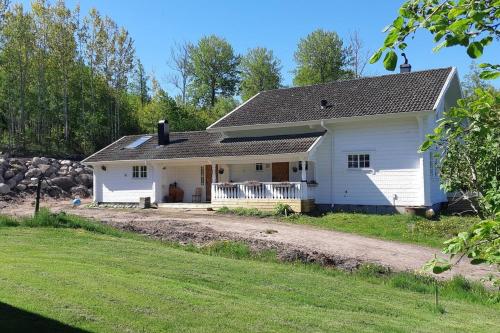 een wit huis met een grindweg ervoor bij Stunning 8-Bed Cabin at lake Skagern in Finnerödja