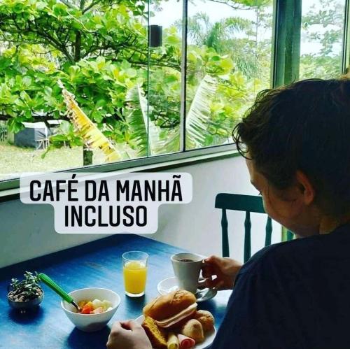 a woman sitting at a table with a plate of food at Pousada Quintal Verde Floripa in Florianópolis