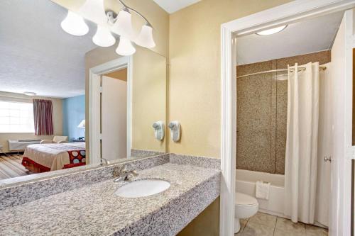 a bathroom with a sink and a mirror and a bed at Super 8 by Wyndham Whites Creek/ Nashville NW Area in Whites Creek