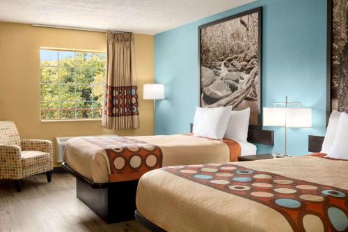 a hotel room with two beds and a chair and a window at Super 8 by Wyndham Whites Creek/ Nashville NW Area in Whites Creek