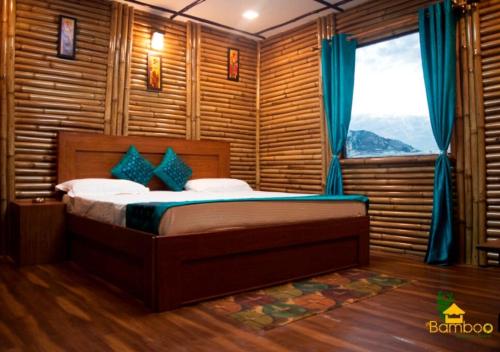a bedroom with a bed with blue curtains and a window at Bamboo Junction Resort - Kanatal, Valley & Mountain View in Dhanaulti
