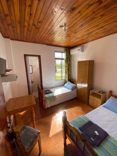 a room with two beds and a table and a desk at Hotel Ibajé in Bagé