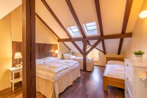 a attic bedroom with two beds and two windows at Janackovo - Riverside Residence in Prague