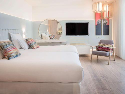 a white bedroom with a large bed and a mirror at Hotel Croisette Beach Cannes Mgallery in Cannes