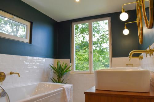 a bathroom with a tub and a sink and a window at La Normande -Piscine- 10 min Pont Audemer 10P in Saint-Symphorien