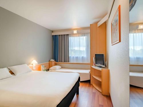 a hotel room with a large bed and a tv at Ibis Częstochowa in Częstochowa