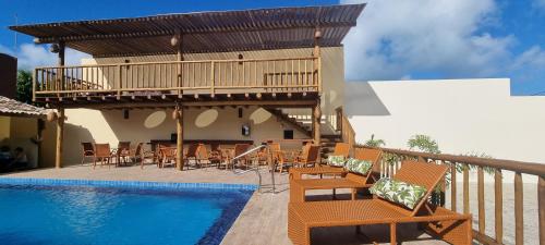 a resort with a pool and chairs and a deck at Pousada Lua Nova Charmosa Pipa in Pipa